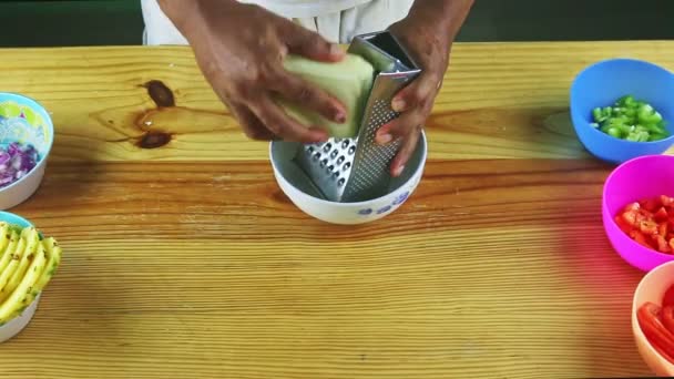 Shora pohled na tmavý muž ruce strouhání sýr na kovové strouhání na dřevěném stole — Stock video