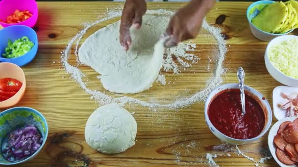 Manzaranın zirvesinde pizza hamurunu ahşap masanın üstünde büyük ve ince yapan adam var. — Stok video