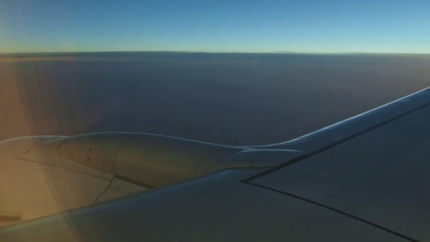 Vue aérienne depuis la fenêtre de l'avion sur l'aile en acier voler au-dessus des nuages blancs pelucheux au coucher du soleil — Video