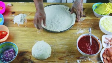 Şefin üst görüntüsü rulo pizza hamurunu çelik fırın tabağına koyar.