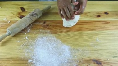 Manzaralı adam ahşap masada beyaz hamuru hızla yoğurur.