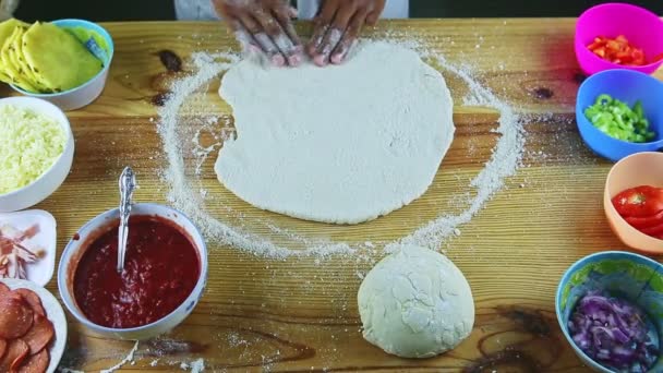 Manzaralı adam, pizza hamurunu büyük ve yuvarlak bir şekilde ahşap masada yapıyor. — Stok video