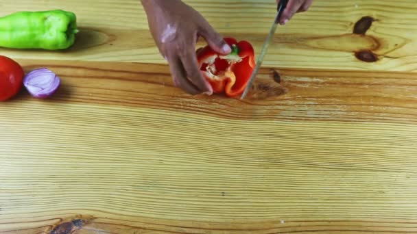 Вид зверху на темношкірих руках людини за ножовим шматочком стиглий солодкий червоний болгарський перець — стокове відео