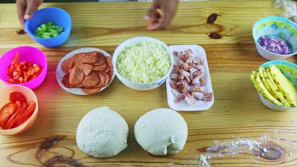 Bovenaanzicht op mensenhanden organiseren verschillende ingrediënten voor het maken van pizza op tafel — Stockvideo