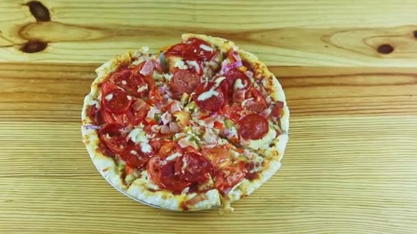 Зум от нарезанной пиццы с пепперони, беконом и овощами на белой тарелке — стоковое видео