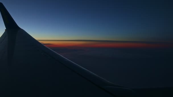 Vue aérienne depuis la fenêtre de l'avion à travers la silhouette de l'aile en acier au coucher du soleil sombre — Video