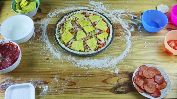 İnsan elinin üst görüntüsü çiğ pizzaya farklı malzemelerle ananas dilimleri koyuyor. — Stok video