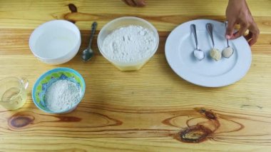 İnsan ellerinin üst görüntüsü kuru mayayla kaşığı suyla dolu derin bir kaseye koyar.