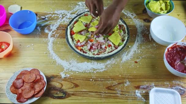 Vista superior en las manos del hombre poner rebanadas de piña en pizza cruda con diferentes ingredientes — Vídeos de Stock