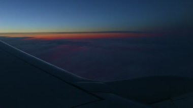 Çelik kanat silueti boyunca karanlık günbatımı gökyüzünde uçak penceresinden hava manzarası