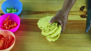 Erkeğin üst görüntüsü ahşap masadan bir grup olgun ananas dilimi alır.