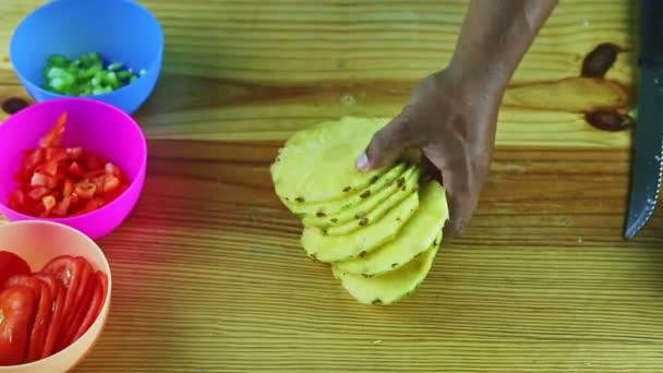 Widok z góry na człowieka przez ręce podjąć grupę dojrzałych plasterków ananasa z drewnianego stołu — Wideo stockowe