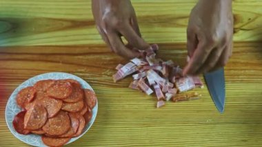 Üst kattaki yakın plan adam ahşap masada dilimlenmiş jambon parçalarını ayırıyor.