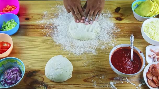 Top view on man by hands making pizza dough round and thin on wooden table — Stock Video
