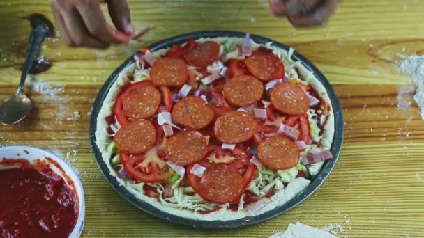 Närbild man för hand sätta pepperoni skivor på rå pizza med många ingredienser — Stockvideo