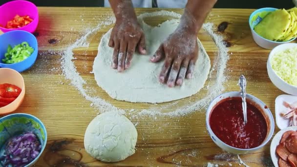 Πάνω άποψη για τον άνθρωπο με τα χέρια κάνοντας ζύμη πίτσα στρογγυλό και λεπτό σε ξύλινο τραπέζι — Αρχείο Βίντεο