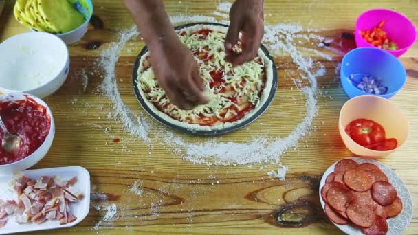 Erkek ellerinin üst görüntüsü, rendelenmiş sert peyniri domates soslu çiğ pizzaya koyar. — Stok video