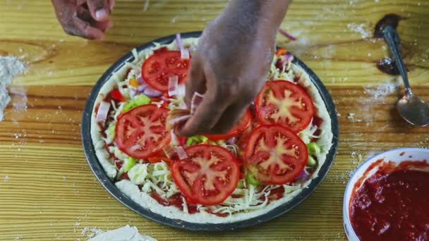 Vista dall'alto primo piano uomo a mano mette pezzi di prosciutto sulla pizza cruda con ingredienti diversi — Video Stock