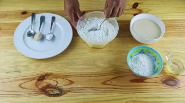 İnsan ellerinin üst görüntüsü kaşıkla beyaz unu kasede servis eder.