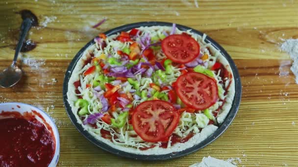 Widok z góry na człowieka przez ręce umieścić pomidory plastry na surowych pizzy z różnych składników — Wideo stockowe