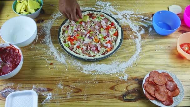 Top view on man hands put ananas skivor på rå pizza med olika ingredienser — Stockvideo