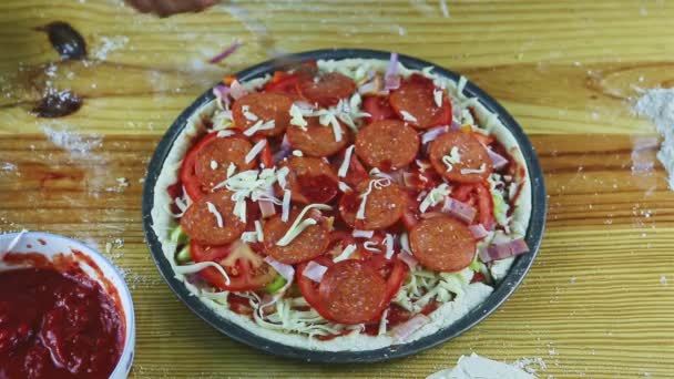 Top view närbild på man händer med sked lägga tomatsås på pizza med pepperoni — Stockvideo