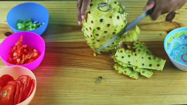 Vrchol pohled na člověka ruce nožem čistý velký ananas od slupky na dřevěném stole — Stock video