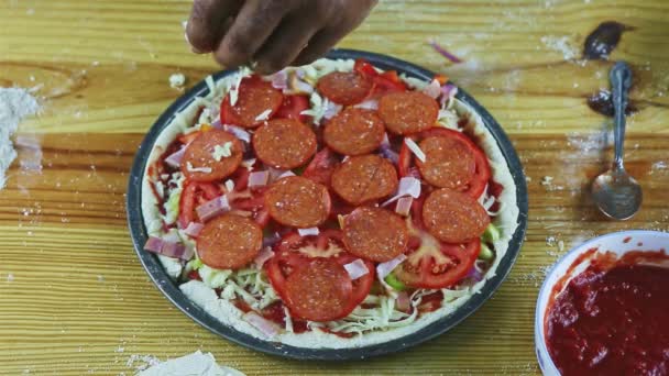 Vista superior sobre as mãos do homem colocar queijo duro ralado na pizza crua com fatias de pepperoni — Vídeo de Stock