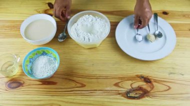 Erkeklerin ellerine kaşıkla tepeden bakınca plastik kasede beyaz una kabartma tozu koyuyorlar.