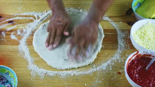 Vue de dessus gros plan homme par mains faire pâte à pizza ronde et mince sur table en bois — Video