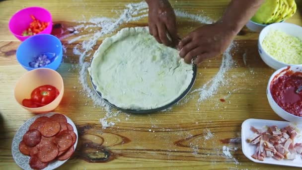 Top view on man by hands makes borders of round pizza dough on still baking dish — Stock Video