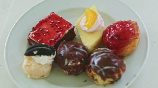 Top view closeup at white plate with different sweet cake pieces assortment — Stock Video