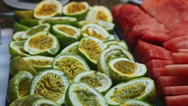 Closeup panorama down at assortment of sliced tropical fruits at food court — Stock Video