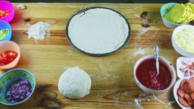 Erkeğin üst görüntüsü yuvarlak pizza hamurunu çelik tencereye koyar.
