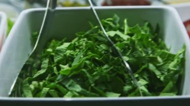 Üst taraf, yemek reyonunda doğranmış yeşil ıspanakla beyaz kase üzerine yakın plan.