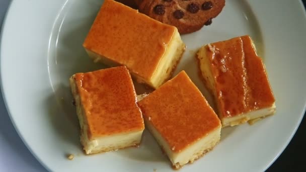 Bovenaanzicht panorama van witte plaat met karamel flan cake stukken en chocolade koekjes — Stockvideo