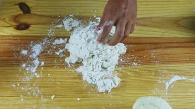 Yukarıdan yakından bakan adam elleri küçük hamur parçalarına beyaz un serpiyor.