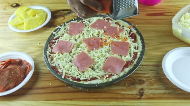 Top view on man by hands grate carrot on raw pizza with different ingredients — Stock Video