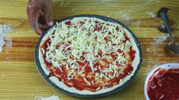 Top ver primer plano en el hombre por las manos pone queso rallado en la pizza con salsa de tomate — Vídeos de Stock