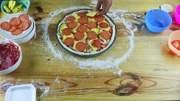 Górny widok na człowieka przez ręce kładzie plasterki ananasa na surowych pizzy z wielu składników — Wideo stockowe