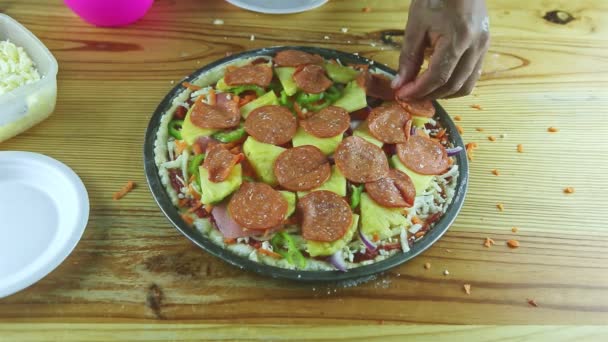 Closeup man by hands put pepperoni slices on raw pizza with different ingredients — Stock Video