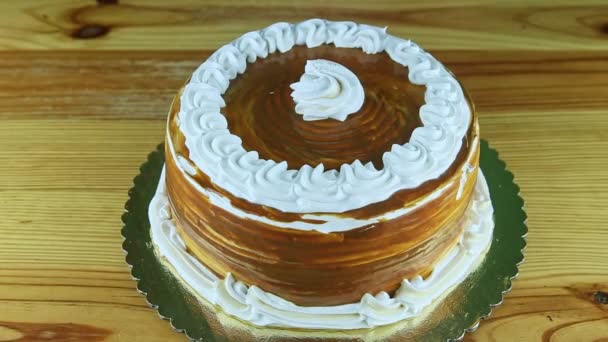 Mãos menina por faca começar a cortar bolo de caramelo inteiro decorado com cobertura de creme branco — Vídeo de Stock