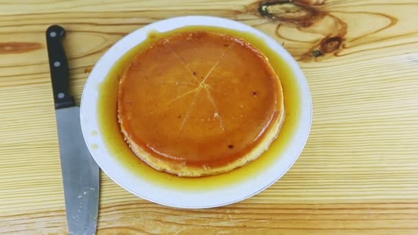 집에서 만든 둥근 플란에서 하얀색 접시에 카라멜 시럽을 바른 위에서 확대 한 모습 — 비디오