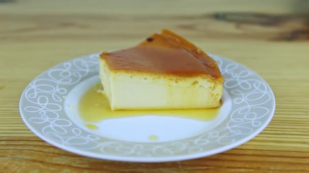 Zoom in bij plak zelfgemaakte melk zachte vlaai met karamelsiroop op witte ronde plaat — Stockvideo