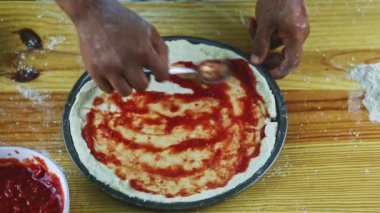 Erkeğin ellerine kaşıkla yukarıdan bak. Yarı bitmiş pizzaya domates sosu koy.