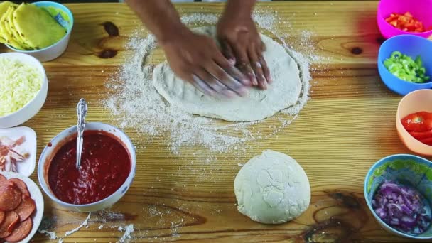 Top view on man by hands making pizza dough big and thin above wooden table — Stock Video
