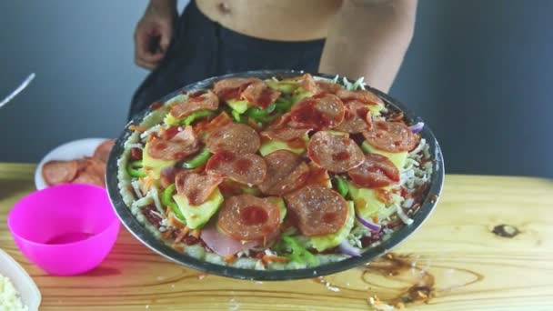 Верхний вид крупным планом на руки человека положить томатный соус на сырой пиццы с пепперони — стоковое видео