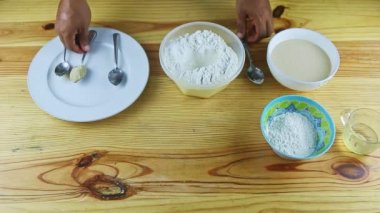 Kaşık kaşıkla insanın üst görüntüsü kuru mayayı suyla dolu derin bir kaseye koydu.