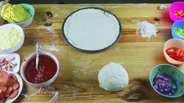Ζουμ πάνω όψης από τυλιγμένη ζύμη πίτσας σερβιρισμένη με διαφορετικά υλικά — Αρχείο Βίντεο