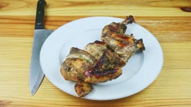 Otlar içinde kavrulmuş tavuk bıçağının yarısı beyaz tabakta bıçakla servis ediliyor.